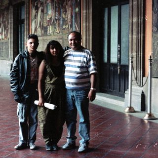 Family poses in a hall with mural artwork.