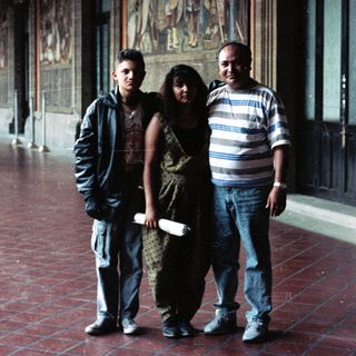 Family poses in a hall with mural artwork.
