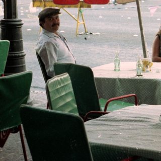 People seated at an outdoor table during rainfall.