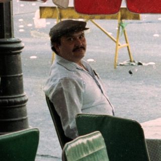 People seated at an outdoor table during rainfall.