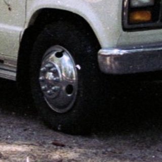 Man stands near a vintage camper van in a campsite.
