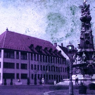 Building and monument in a town square, likely historical.