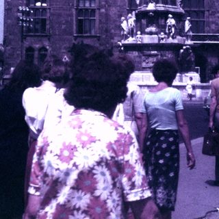 People view a fountain in front of a building.