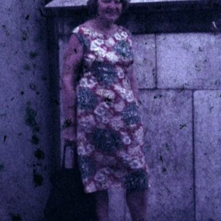 Woman stands near a large, ornate statue outdoors.