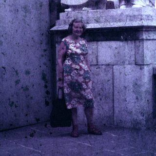 Woman stands near a large, ornate statue outdoors.
