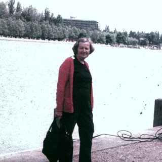 Person stands near a boat on a waterfront dock.