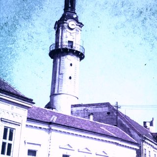 Clock tower with a spire and building facade.