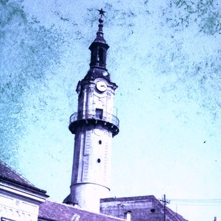 Clock tower with a spire and building facade.