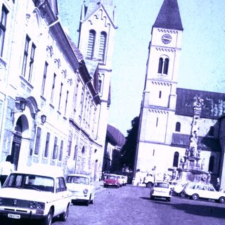 Street scene with church and vintage cars in a town.