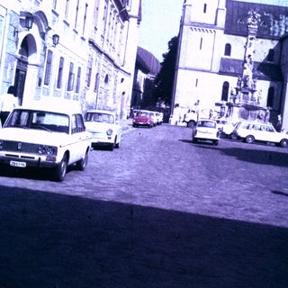 Street scene with church and vintage cars in a town.