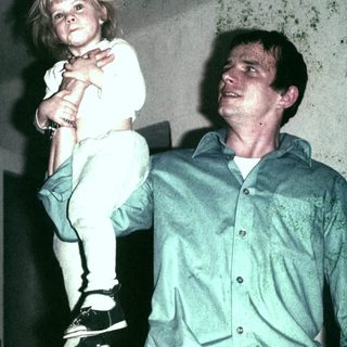 Man carrying a child indoors, possibly a father and daughter.