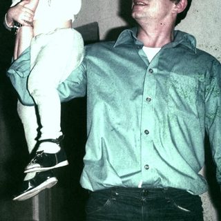 Man carrying a child indoors, possibly a father and daughter.