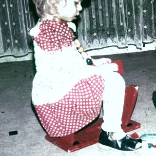 Two young girls playing with building blocks on a carpet.