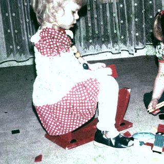 Two young girls playing with building blocks on a carpet.