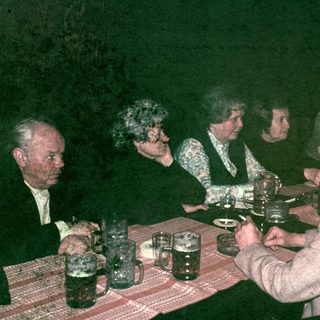 Group of people seated at a table, drinking beer.