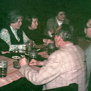 Group of people seated at a table, drinking beer.