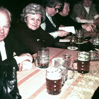 Group of people seated at a table with beer mugs.