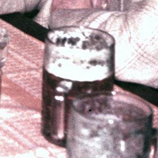 Men sit at a table with drinks, appearing to converse.