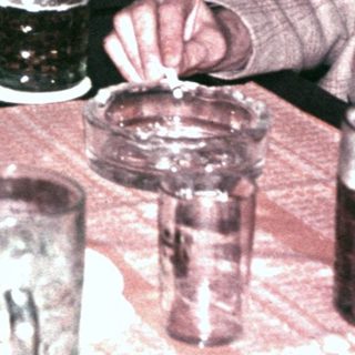 Men sit at a table with drinks, appearing to converse.
