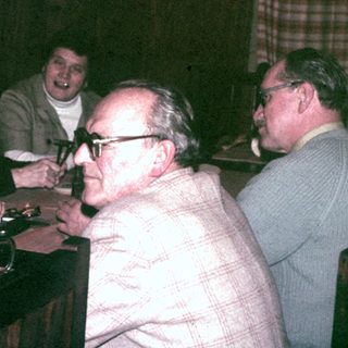 Group of people seated at a table, seemingly socializing.