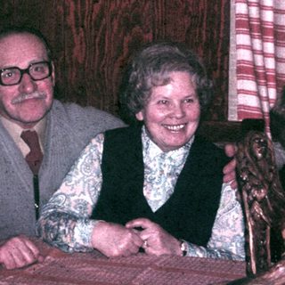 Four people are seated at a table, smiling.