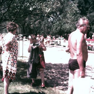 People relax and socialize near a beach on a sunny day.