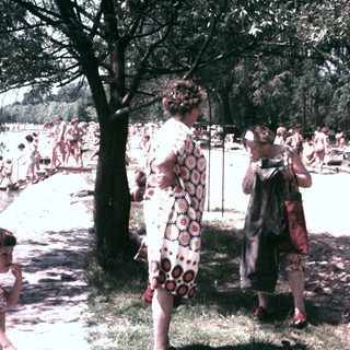 People relax and socialize near a beach on a sunny day.