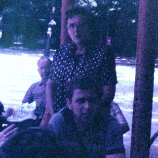 Men seated at a table outdoors, appearing to socialize.
