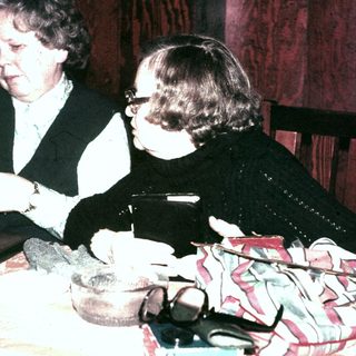 Two women seated at a table, appearing to be writing.