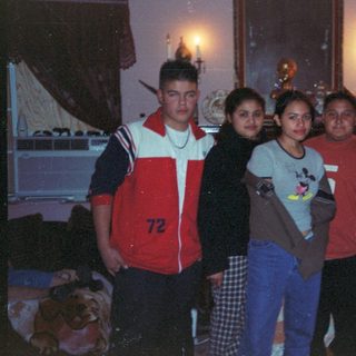 Here's a brief summary of the image: Group of young people posing indoors, likely family or friends.