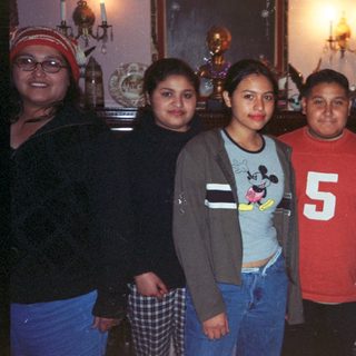 Group of five young people stand indoors with decor visible.