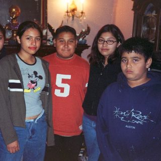 Group of five young people stand indoors with decor visible.