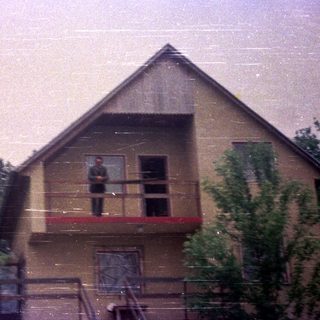 Man stands on a balcony of a multi-story building.