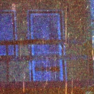 Blue toned image shows a house with a balcony.