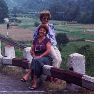 People relaxing on a roadside with a mountain view.