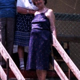 Couple stands on steps in front of an apartment building.