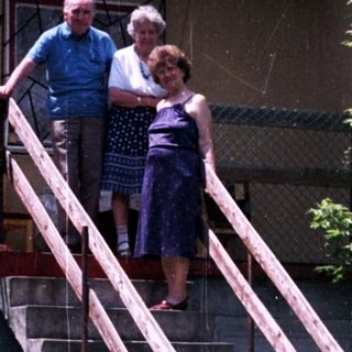 Couple stands on steps in front of an apartment building.