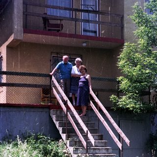 Couple stands on steps in front of an apartment building.