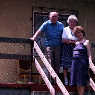 Couple stands on steps in front of an apartment building.