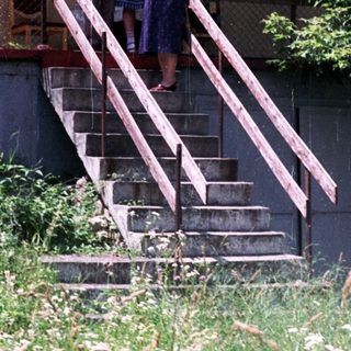 Couple stands on steps in front of an apartment building.