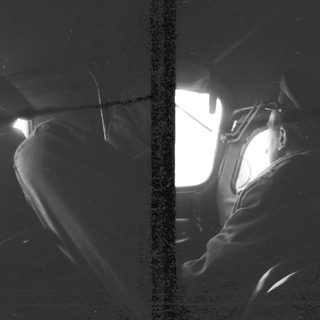 Here's a brief summary of the image: Man in uniform looking out of an aircraft window.