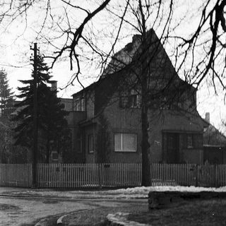 Black and white image of a house with a fence.