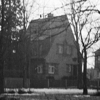 Monochromatic image depicts a house with bare trees and snow.