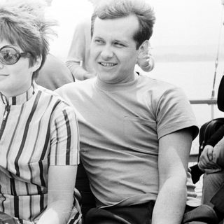 Here's a brief summary of the image: Two people seated, smiling, on a boat.