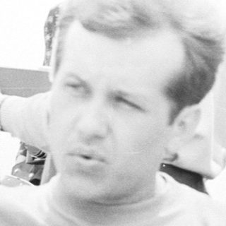 Men on a boat, some smoking, in black and white.