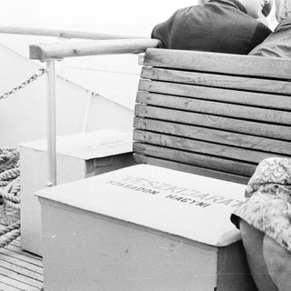 People sitting on a boat with a box in between.