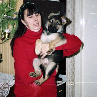 Woman holding a puppy near a Christmas tree.