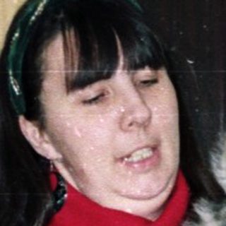 Woman holding a puppy near a Christmas tree.