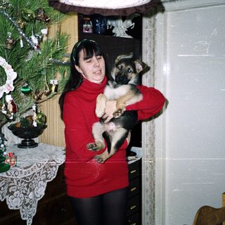 Woman holding a puppy near a Christmas tree.