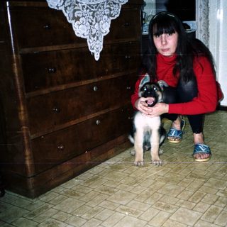 Woman crouches near a puppy in a tiled room.